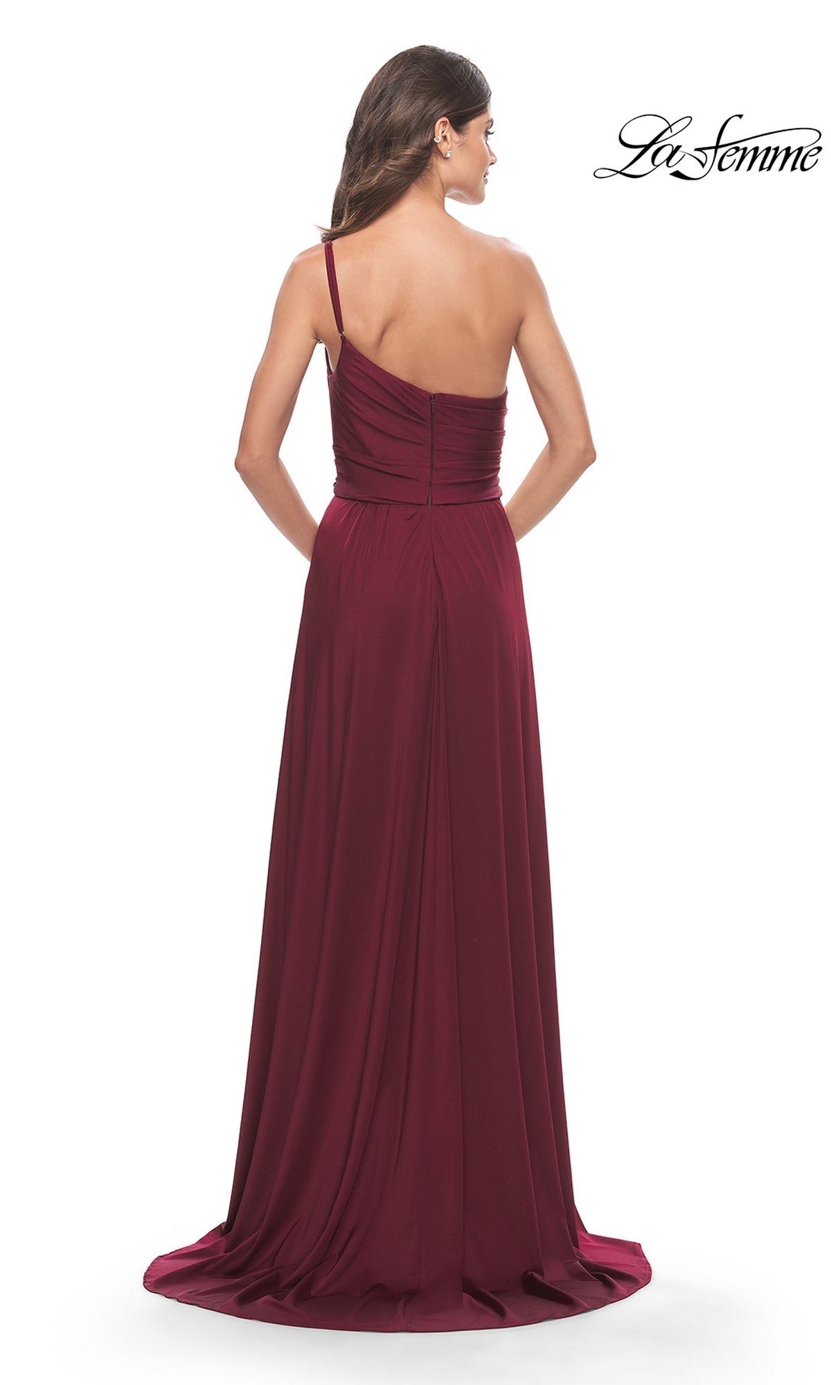 A woman faces away from the camera in a floor-length, burgundy One-Shoulder Long La Femme Formal Dress 31170, featuring subtle pleats and a slight train. The La Femme logo appears in the corner.